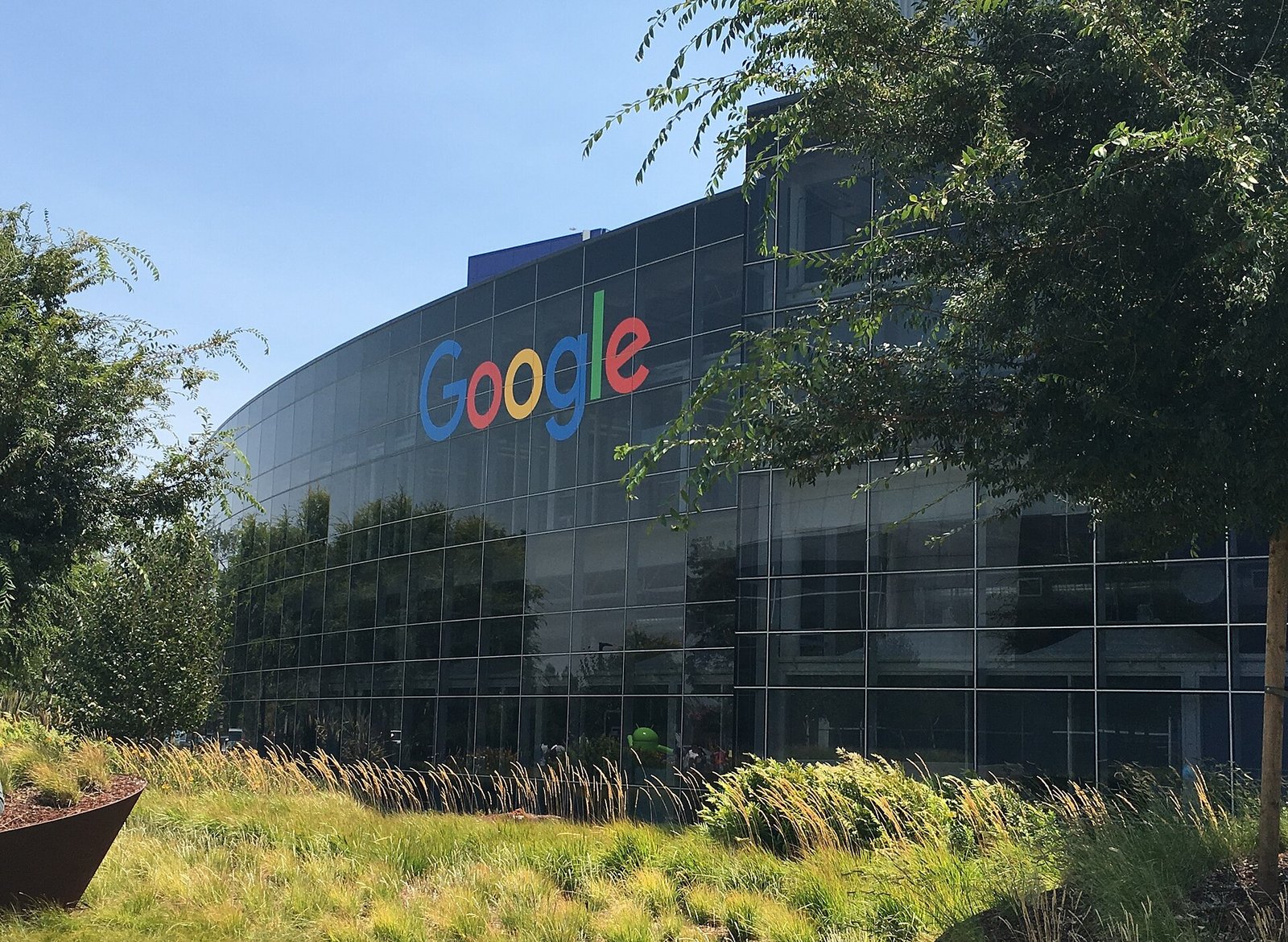 맑은 날 나무와 풀 너머로 보이는 구글 본사 유리 건물과 커다란 Google 글자