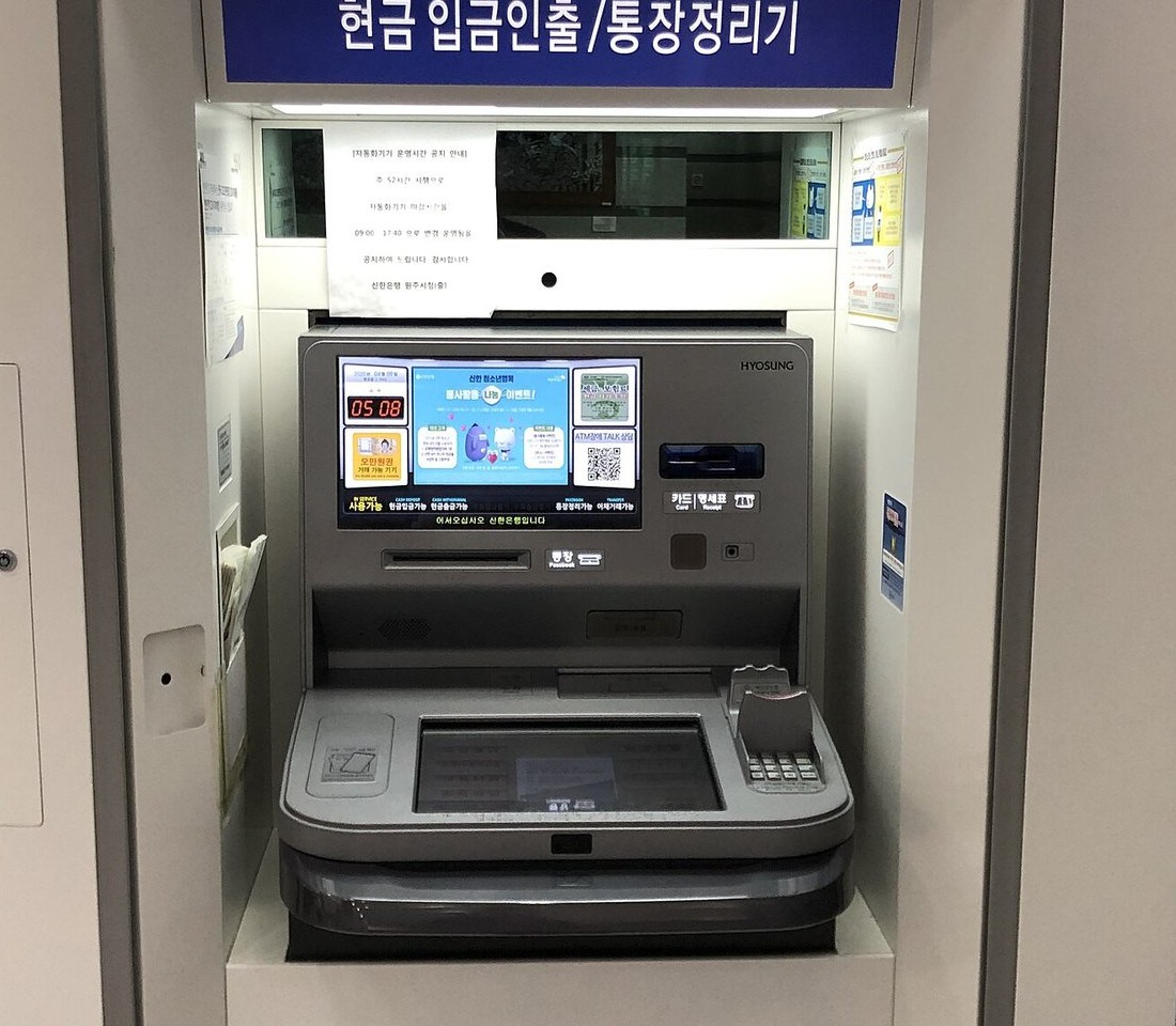 은행 자동화기기 부스. 위에 '현금 입금인출/통장정리기' 표지판이 있고 화면과 카드 투입구, 통장 투입구가 보인다