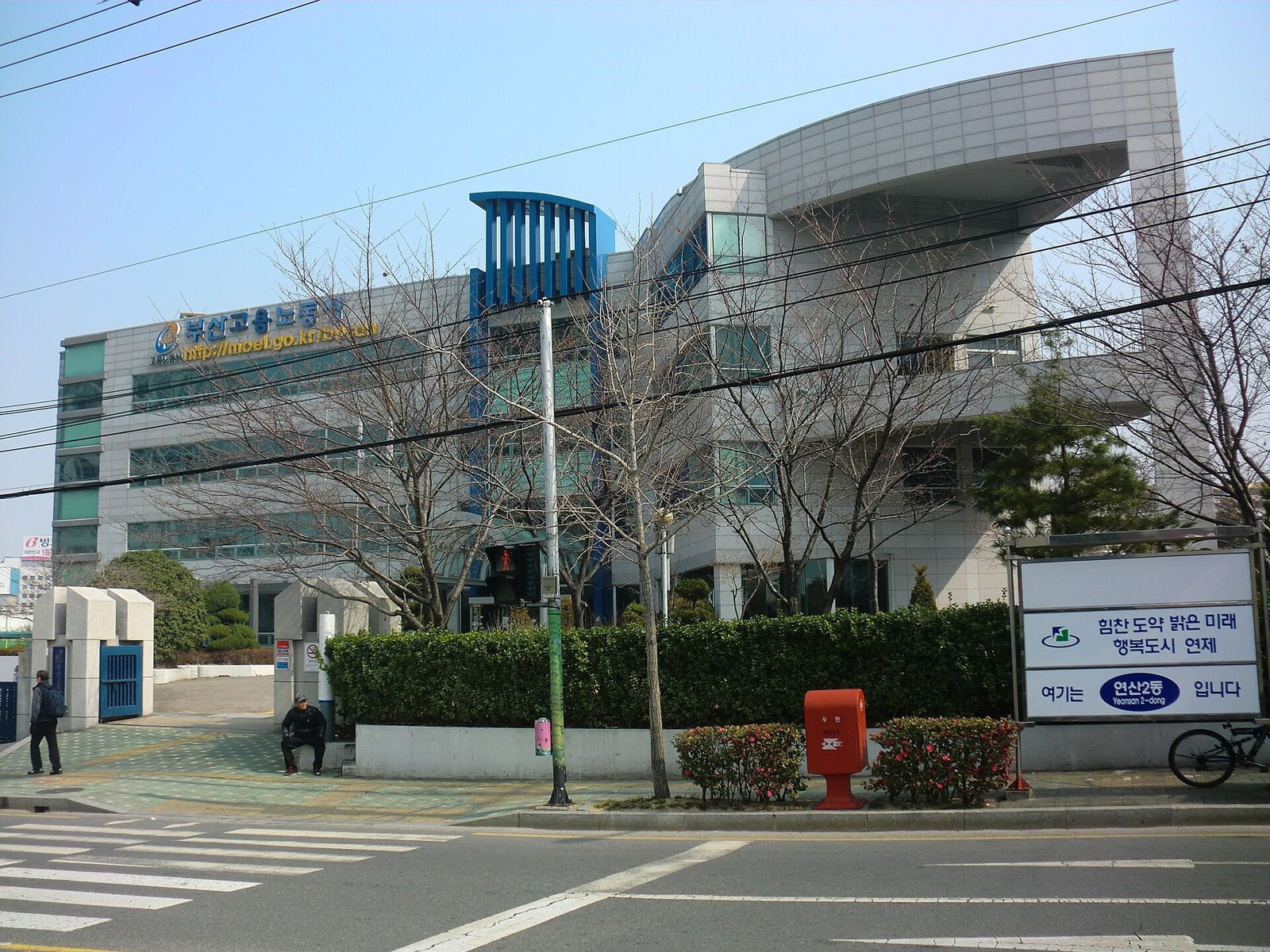 길가에 선 은색 곡선 지붕의 4층 건물 외벽에 부산고용노동청 간판이 붙어 있고, 앞쪽에 앙상한 가로수와 횡단보도가 보인다